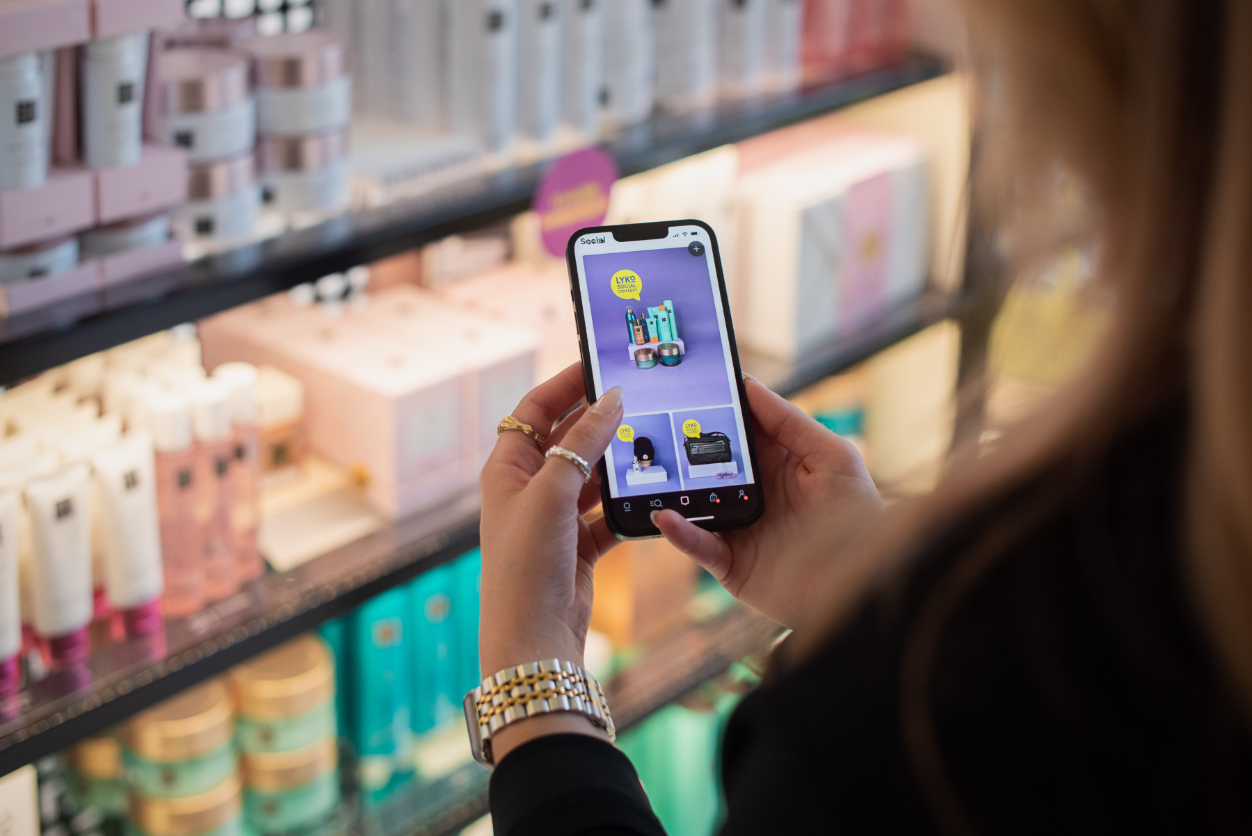En kund i en Lyko-butik håller upp mobilen med Lyko Social-flödet i appen.